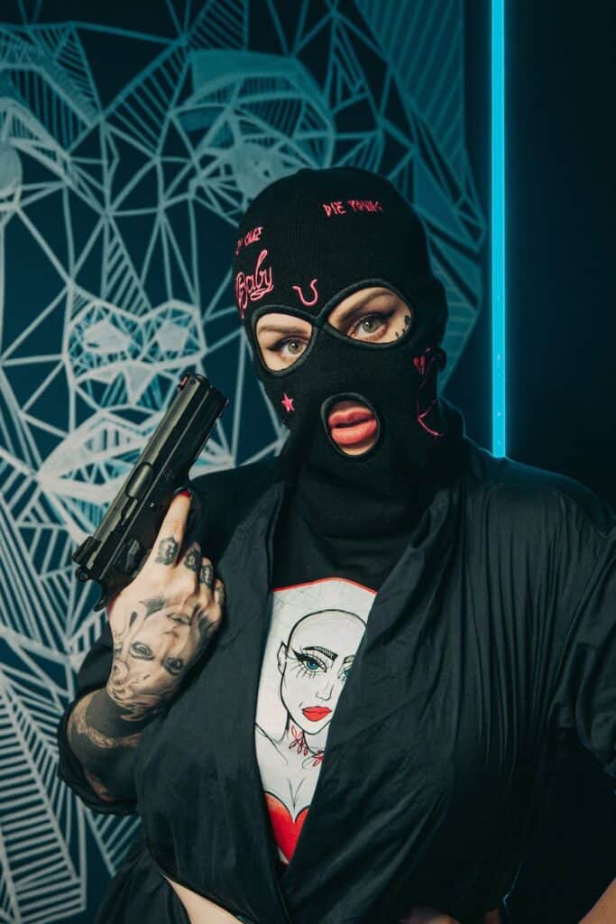 lady burglar in mask with gun and tattoos