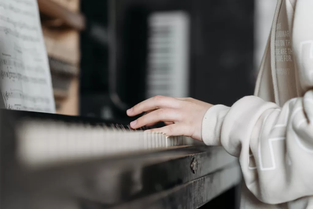 person in white long sleeve shirt playing piano