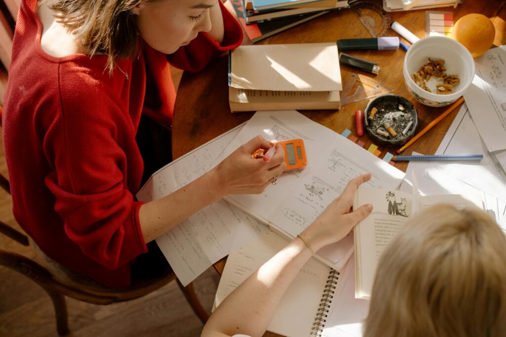 girl in red long sleeve shirt writing on white paper