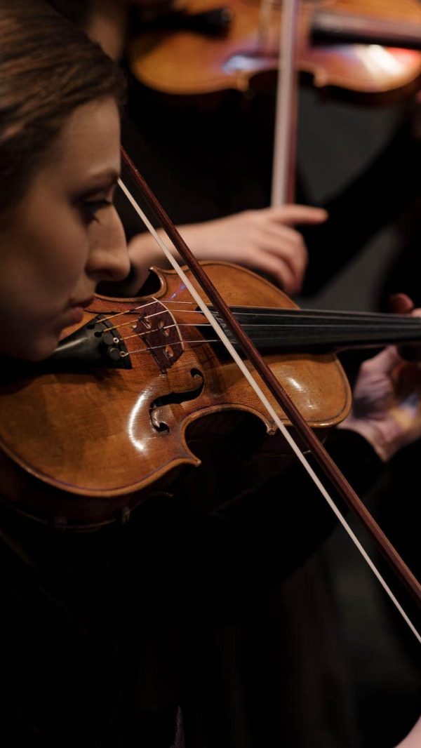 boy playing violin in black room